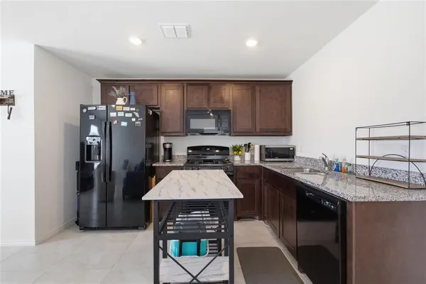 a kitchen with stainless steel appliances granite countertop a refrigerator a sink a stove a dining table and chairs