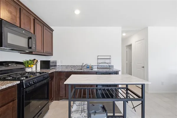 a kitchen with stainless steel appliances kitchen island granite countertop a stove a sink and a microwave
