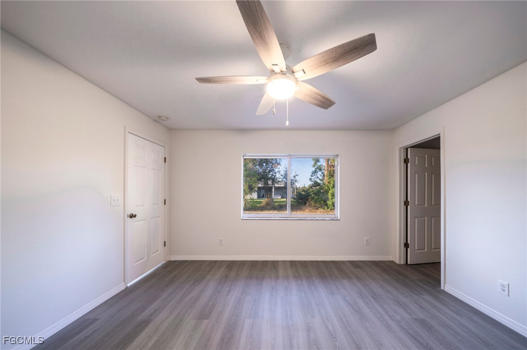 4306 11th Street Southwest Lehigh Acres, FL 33976 - Photo 9 of 17 an empty room with wooden floor chandelier fan and windows