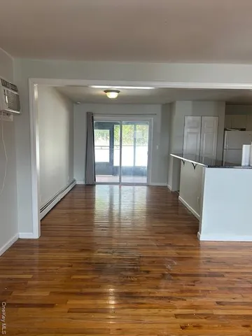 a view of empty room with wooden floor and window