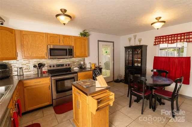 a kitchen with stainless steel appliances a stove a sink dishwasher a refrigerator cabinets and a dining table with wooden floor