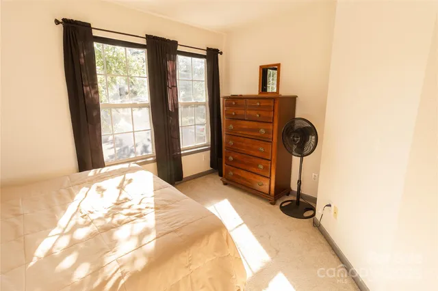a bedroom with a bed and two windows
