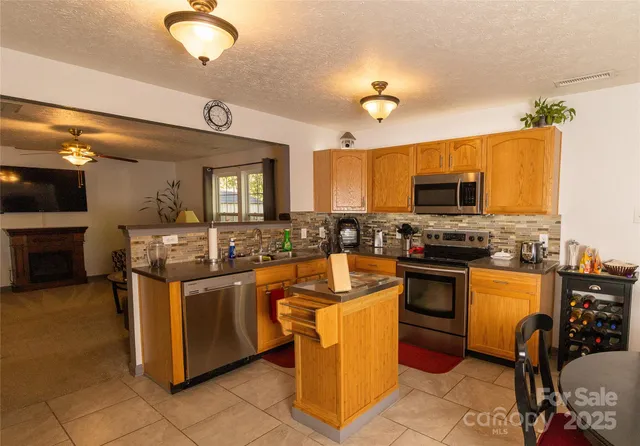 a kitchen with stainless steel appliances granite countertop a stove top oven a sink dishwasher a dining table and chairs with wooden floor