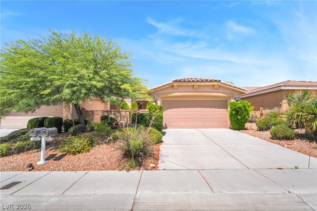 5389 Progresso Street Las Vegas, NV 89135 - Photo 3 of 41 Well-maintained desert landscaping frames this welcoming residence, boasting a spacious concrete driveway leading to the attached garage.