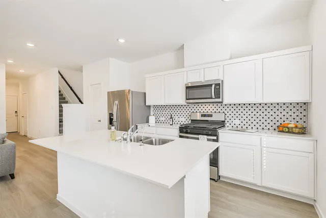 a kitchen with stainless steel appliances a stove a sink a refrigerator a microwave a refrigerator and cabinets