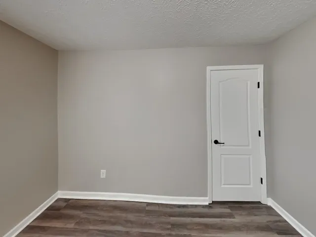 a view of an empty room with wooden floor and a ceiling fan