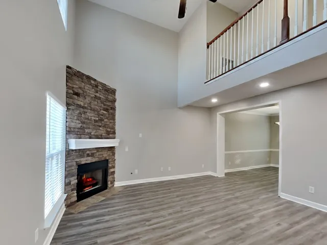 a view of an empty room with wooden floor fireplace and a window