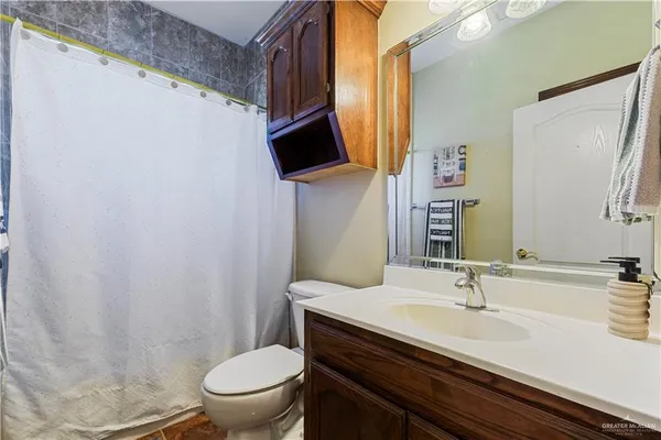a bathroom with a granite countertop sink toilet and mirror