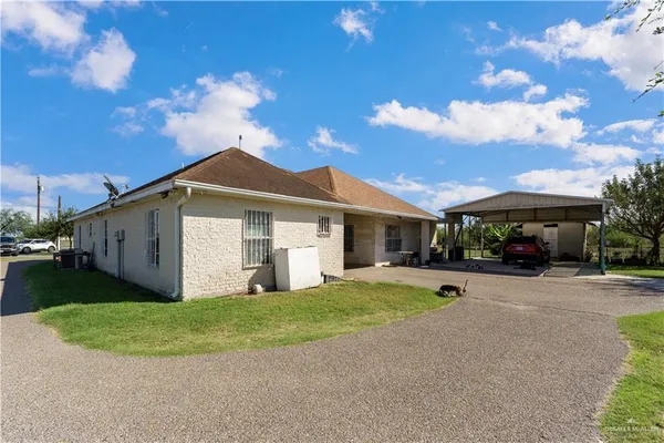a view of a white house with a big yard and large trees