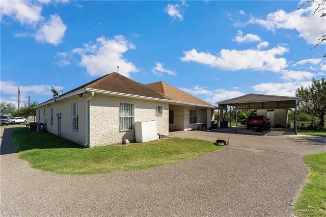 a view of a white house with a big yard and large trees