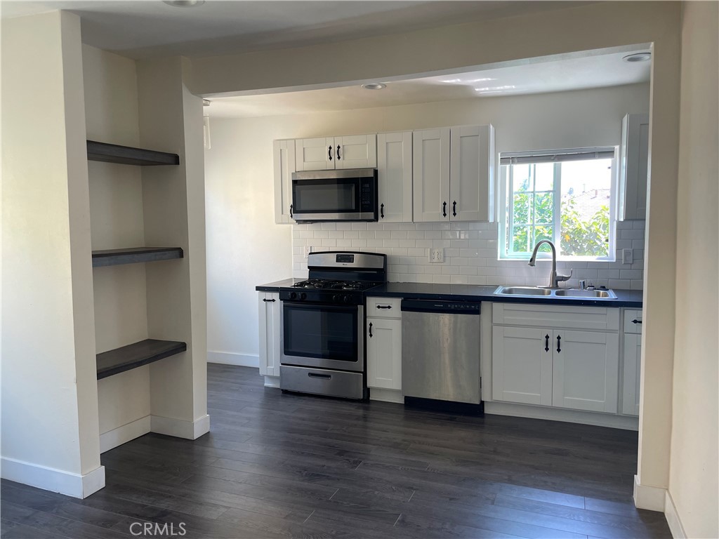 1325 1/2 Douglas Street Los Angeles, CA 90026 - Photo 2 of 23 a kitchen with stainless steel appliances white cabinets and a wooden floor