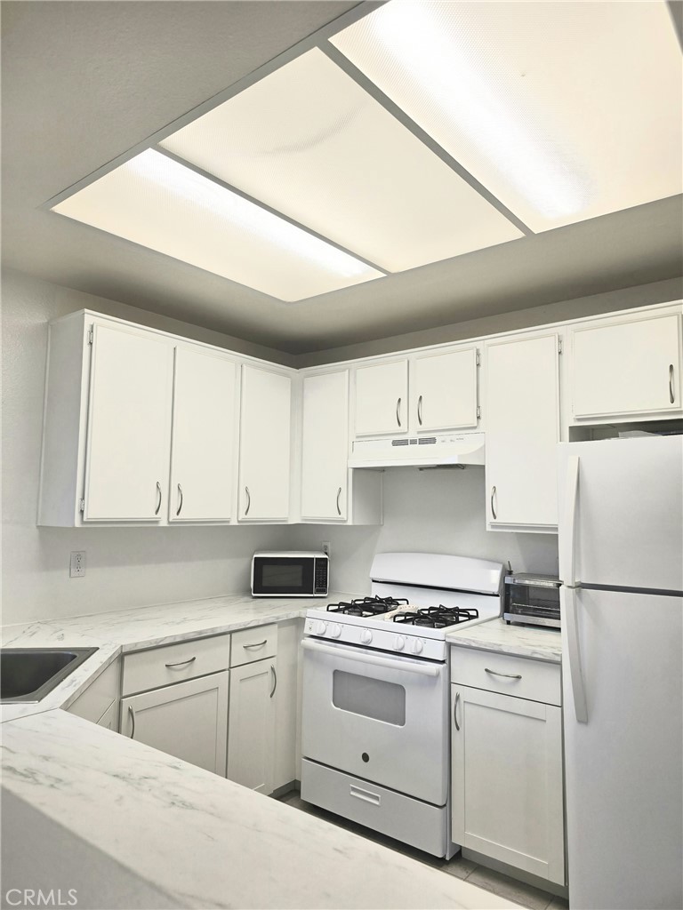 36839 Goldenview Way Palmdale, CA 93552 - Photo 11 of 20 a kitchen with a stove a refrigerator and white cabinets
