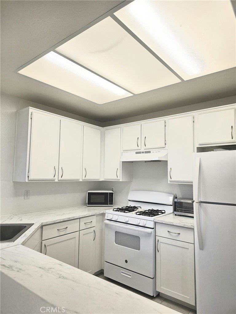36839 Goldenview Way Palmdale, CA 93552 - Photo 13 of 20 a kitchen with a stove a refrigerator and white cabinets