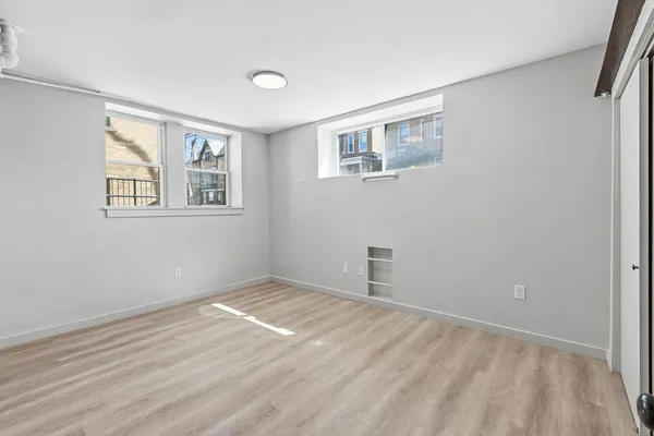 a view of empty room with wooden floor and fan