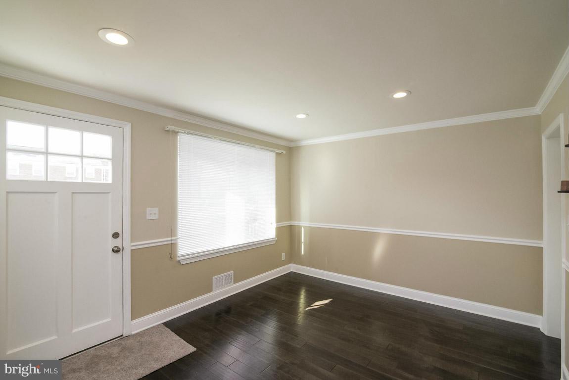 718 Middlesex Road Baltimore, MD 21221 - Photo 3 of 30 an empty room with wooden floor and windows