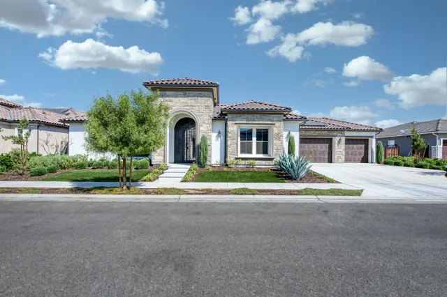a front view of a house with a garden and trees