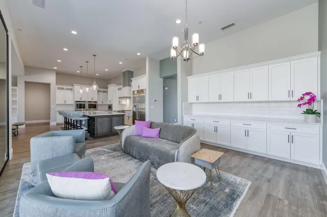 a view of a dining room and livingroom with furniture wooden floor a rug a flat screen tv a painting and a chandelier
