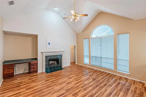 a view of an empty room with wooden floor fireplace and a window