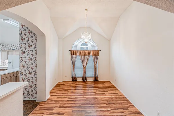 a view of a livingroom with wooden floor and a hallway