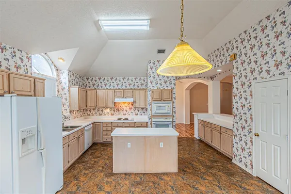 a room with kitchen island stainless steel appliances a stove a sink dishwasher and a refrigerator