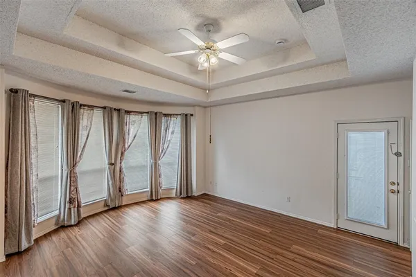 a view of an empty room with wooden floor and a ceiling fan
