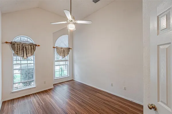 a view of an empty room with window and wooden floor