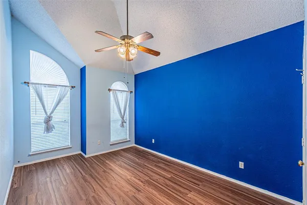 a view of empty room with wooden floor and fan