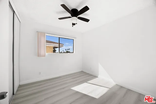 an empty room with wooden floor and ceiling fan