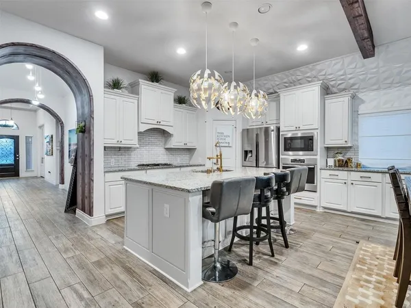 a kitchen with stainless steel appliances kitchen island granite countertop a table chairs sink and cabinets