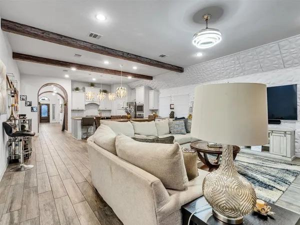 a living room with furniture a flat screen tv and kitchen view