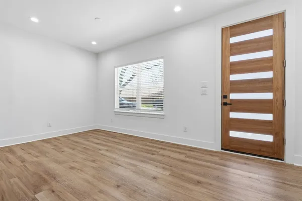 an empty room with wooden floor closet and windows