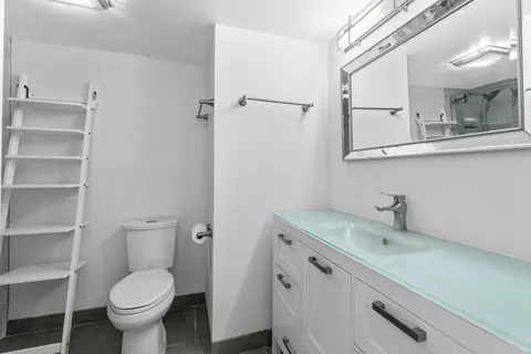 a bathroom with a granite countertop toilet sink and mirror
