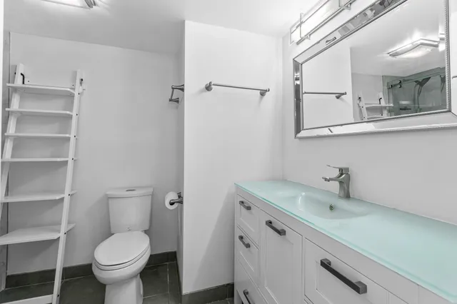 a bathroom with a granite countertop toilet sink and mirror