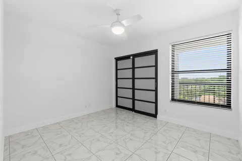an empty room with windows and fan