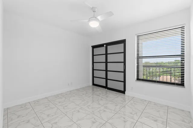 an empty room with windows and fan