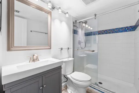 a bathroom with a sink a mirror a toilet and shower