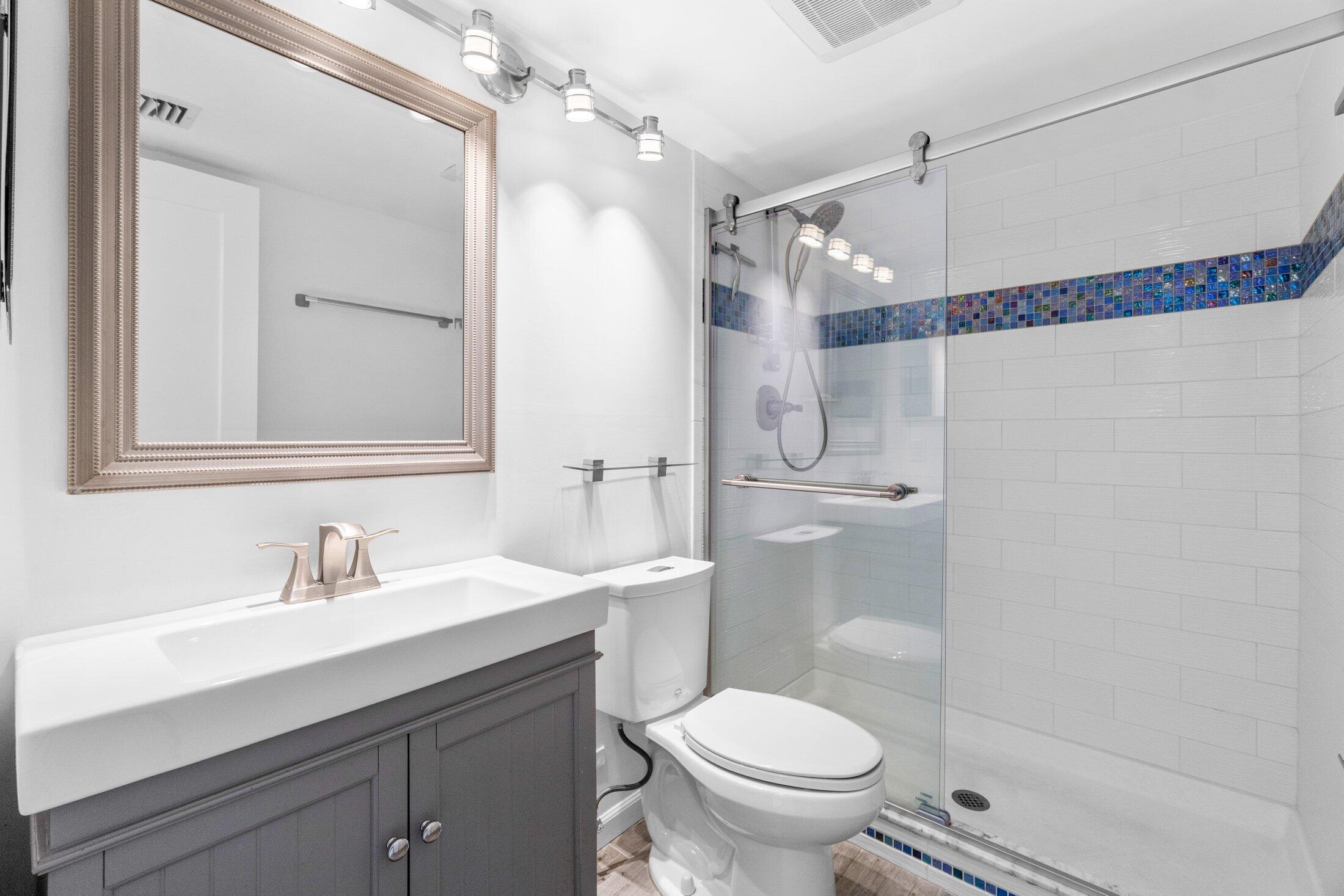 6562 Boca Del Mar Drive, Unit 527 Boca Raton, FL 33433 - Photo 21 of 38 a bathroom with a sink a mirror a toilet and shower