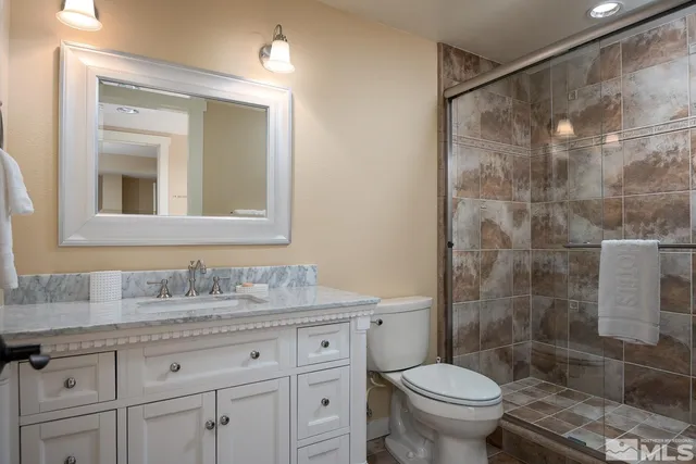 a bathroom with a granite countertop sink a toilet and a shower