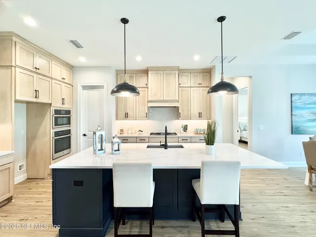 a kitchen with stainless steel appliances kitchen island granite countertop a sink a stove a refrigerator and island with wooden floor