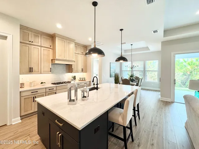 a kitchen with stainless steel appliances kitchen island granite countertop a stove a sink a refrigerator a center island a dining table and chairs with wooden floor