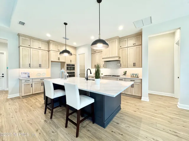 a kitchen with stainless steel appliances kitchen island wooden floors and white cabinets