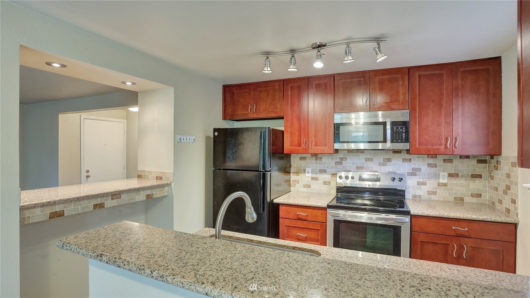 11002 Southeast Petrovitsky Road, Unit H101 Renton, WA 98055 - Photo 13 of 30 a kitchen with kitchen island granite countertop a sink stove and refrigerator