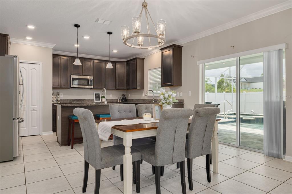 7242 Landmark Drive Spring Hill, FL 34606 - Photo 11 of 45 a dining room with stainless steel appliances kitchen island granite countertop a dining table chairs and a refrigerator