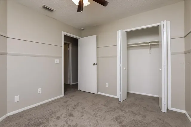 an empty room with closet and a ceiling fan