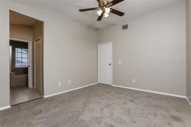 a view of an empty room with closet and a chandelier fan