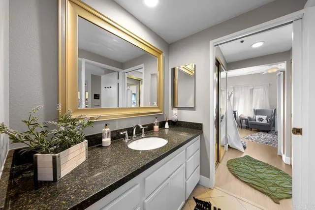 a bathroom with a granite countertop sink and a mirror
