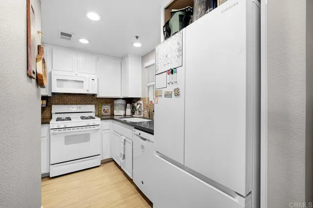 a kitchen with white cabinets and white appliances