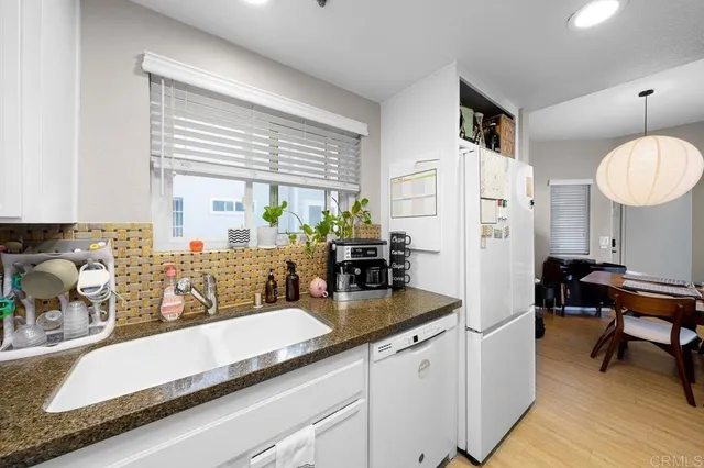 a kitchen with granite countertop a sink a counter cabinets and stainless steel appliances