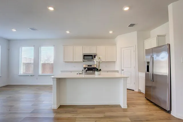 a kitchen with stainless steel appliances granite countertop a refrigerator a stove and a wooden floors