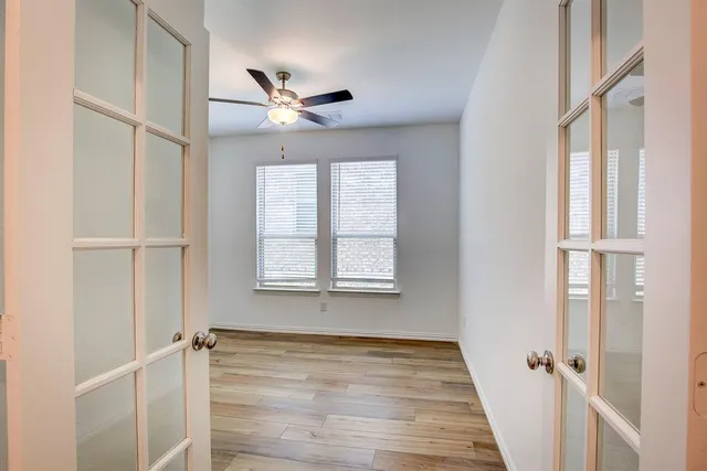 a view of an empty room with a window and wooden floor